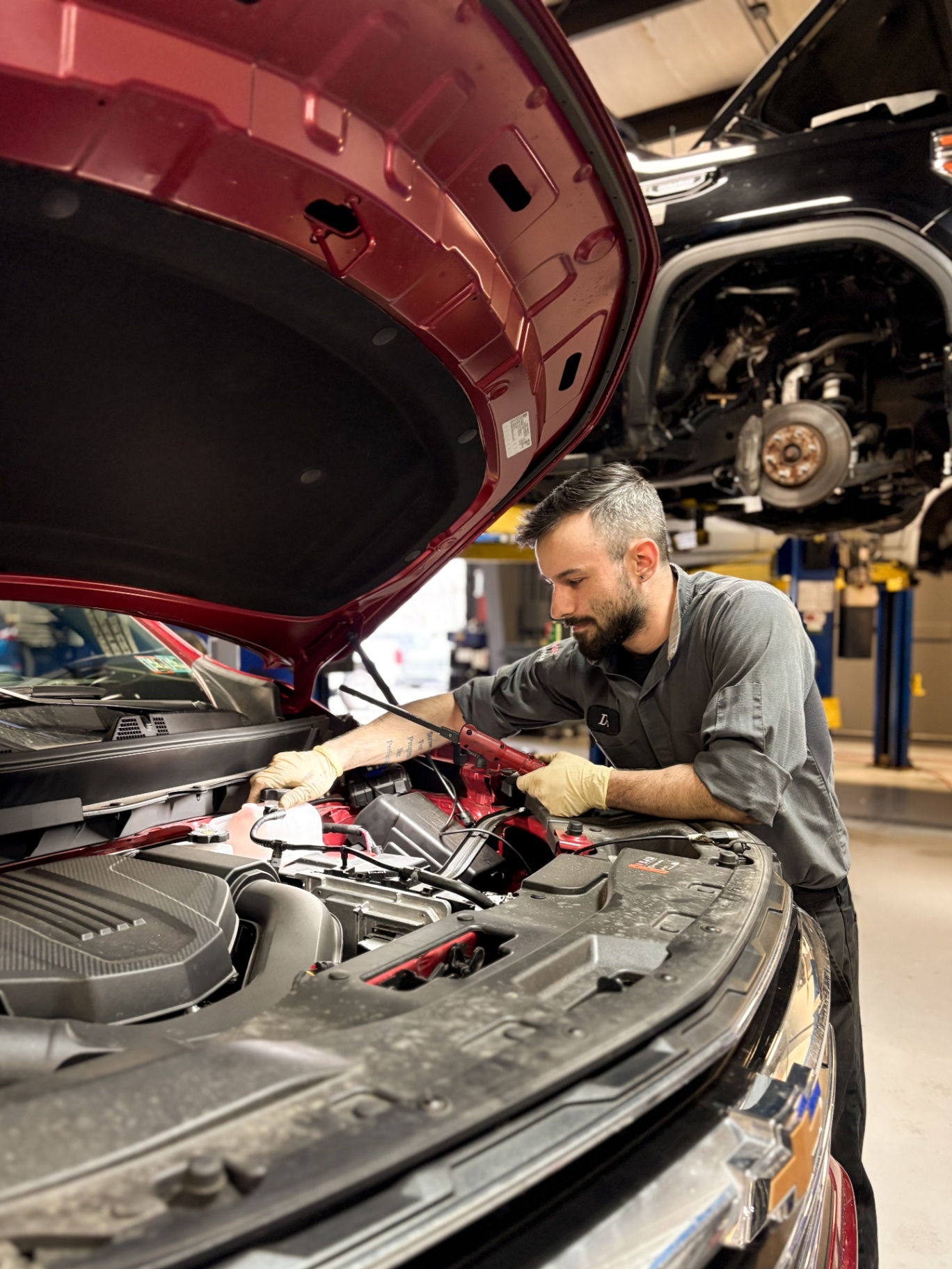 Experienced technician working under the hood of a vehicle at a dealership.