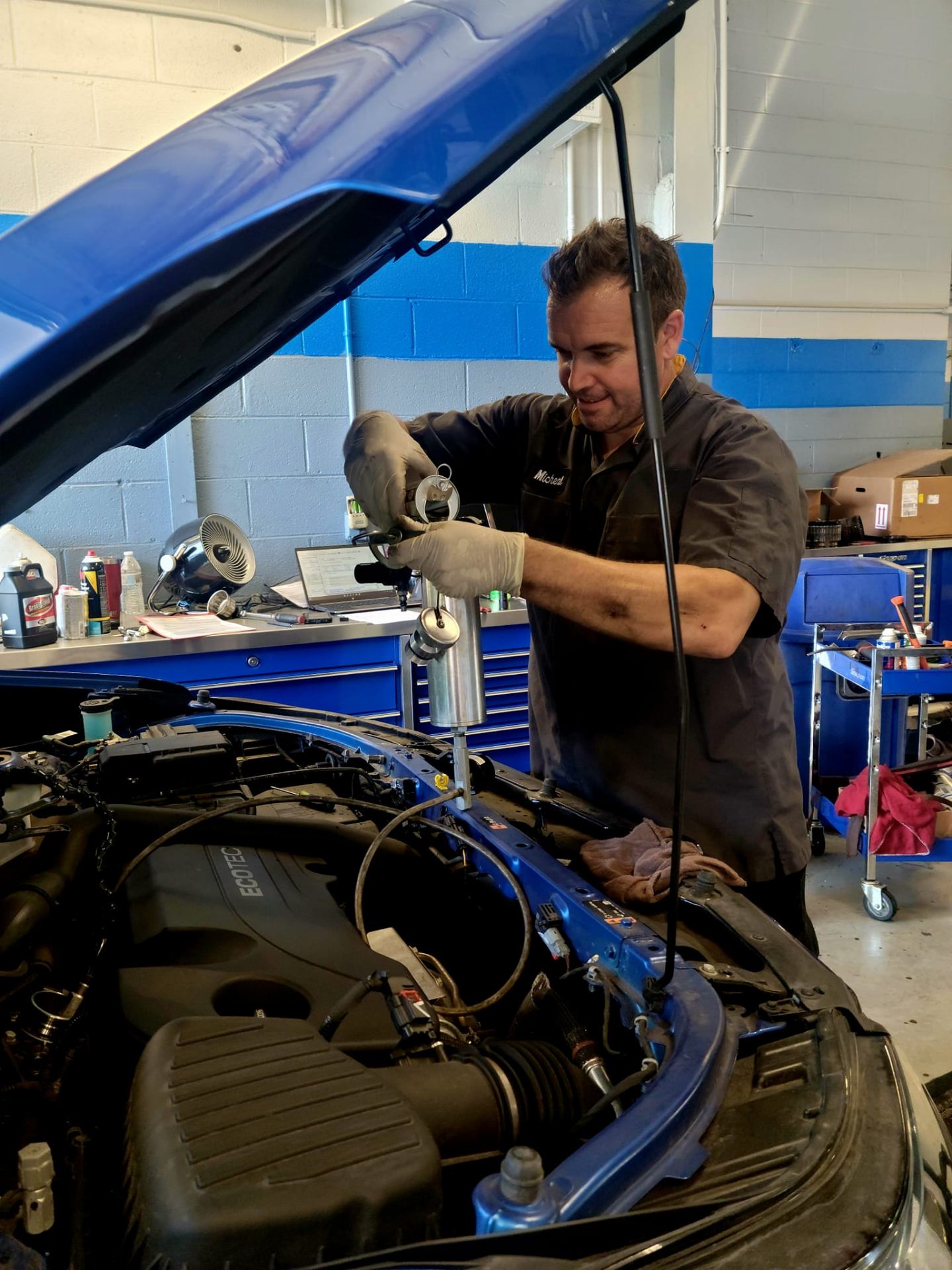 Technician working on an engine bay in a well-lit service department.