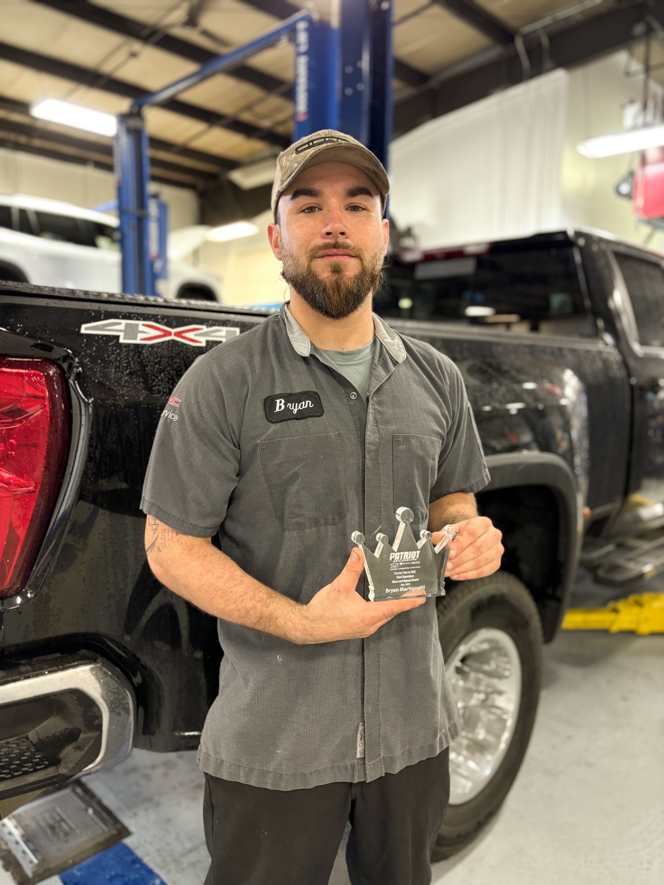 Bryan, a Patriot GMC technician, holding the crown-shaped Above & Beyond fleet operations award