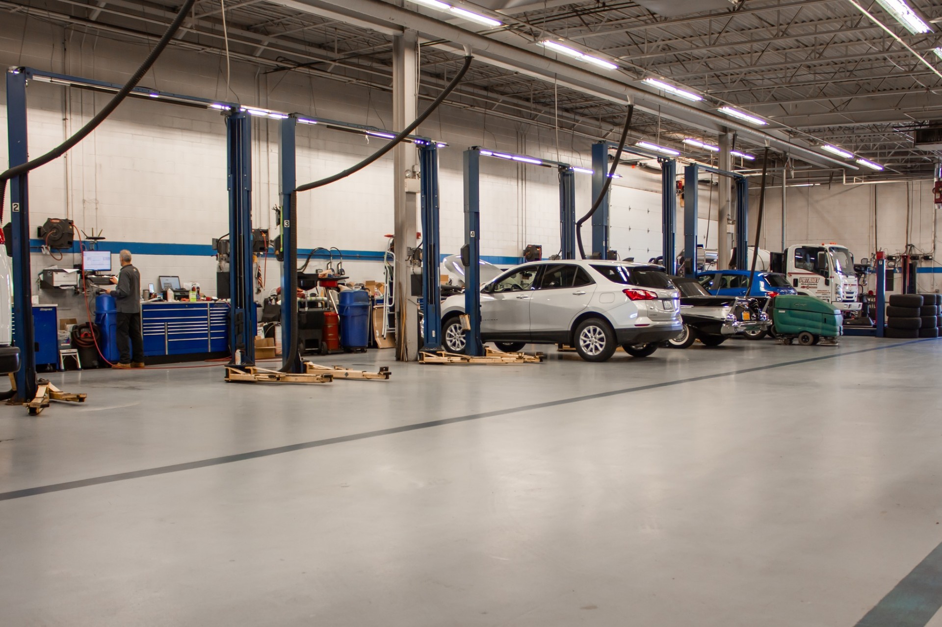 Wide view of an automotive service shop floor with multiple bays and lifts.