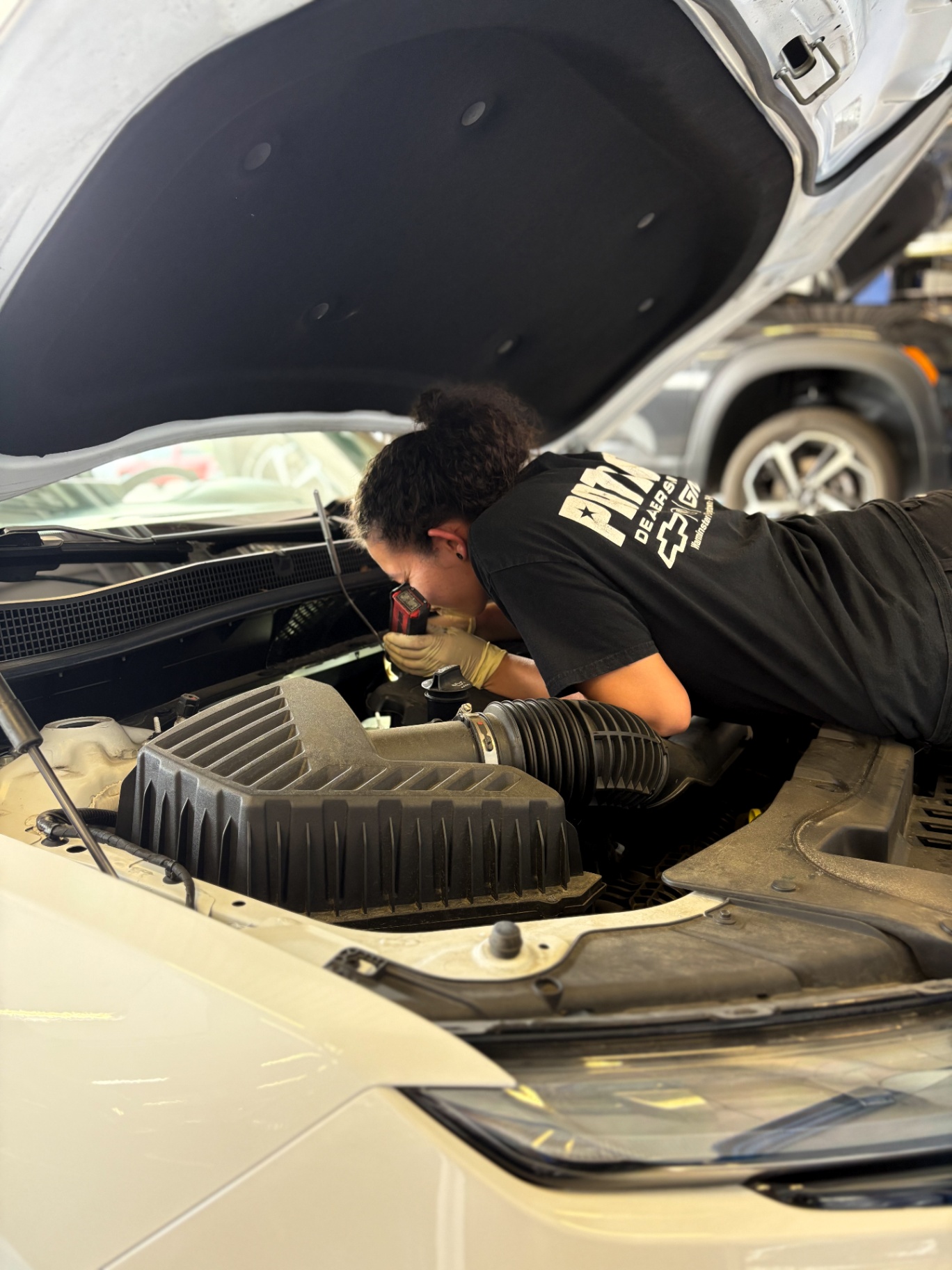 Patriot technician inspecting an engine bay with a work light