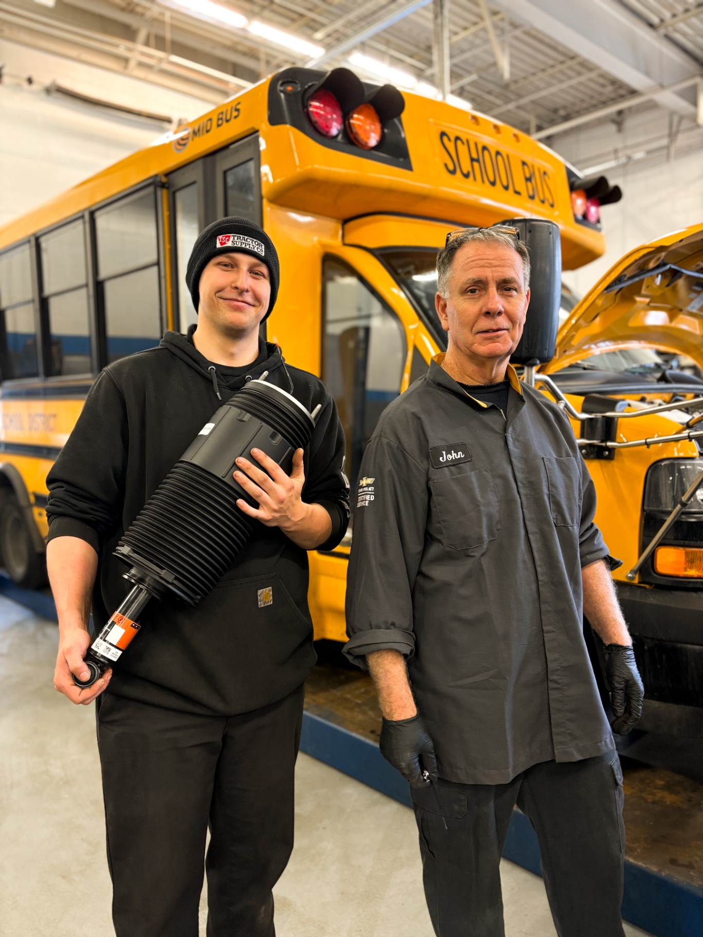Younger technician working on a strut assembly at a service shop.